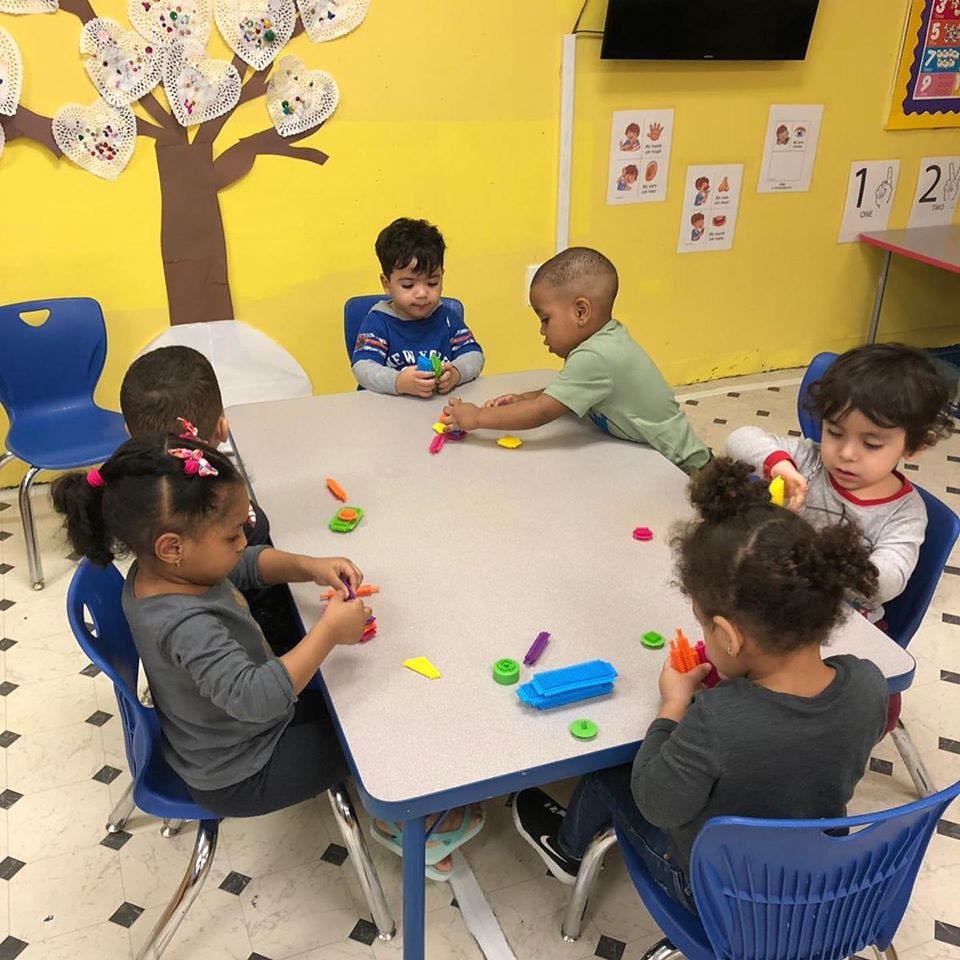 Children playing with colorful clay at a table in a classroom