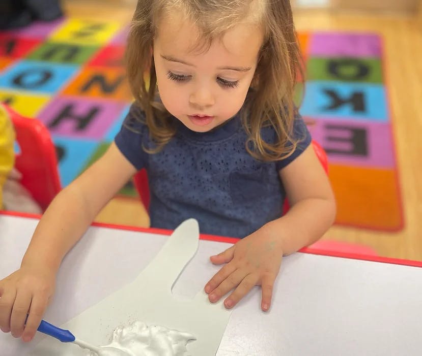 Child painting on a white paper cutout