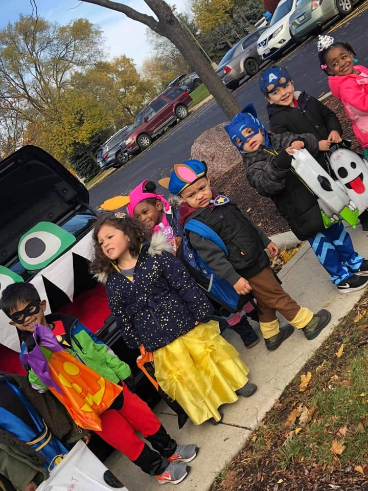 Children in costumes standing by a car decorated with monster eyes and teeth