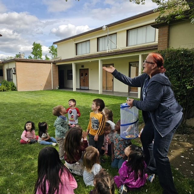 Adult showing children a butterfly habitat outdoors