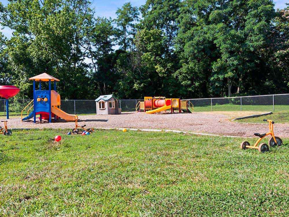 Playground area with slides, playhouses, and trikes on a sunny day