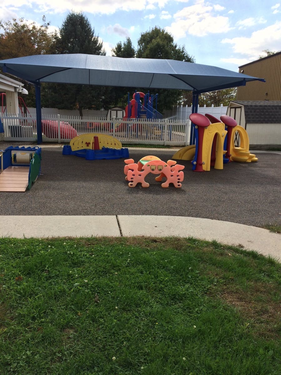 Outdoor playground with various colorful play structures under a blue canopy