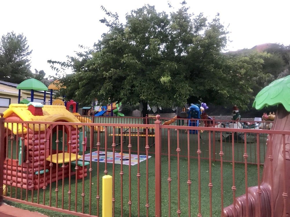Outdoor playground with playhouses and slides behind a fence