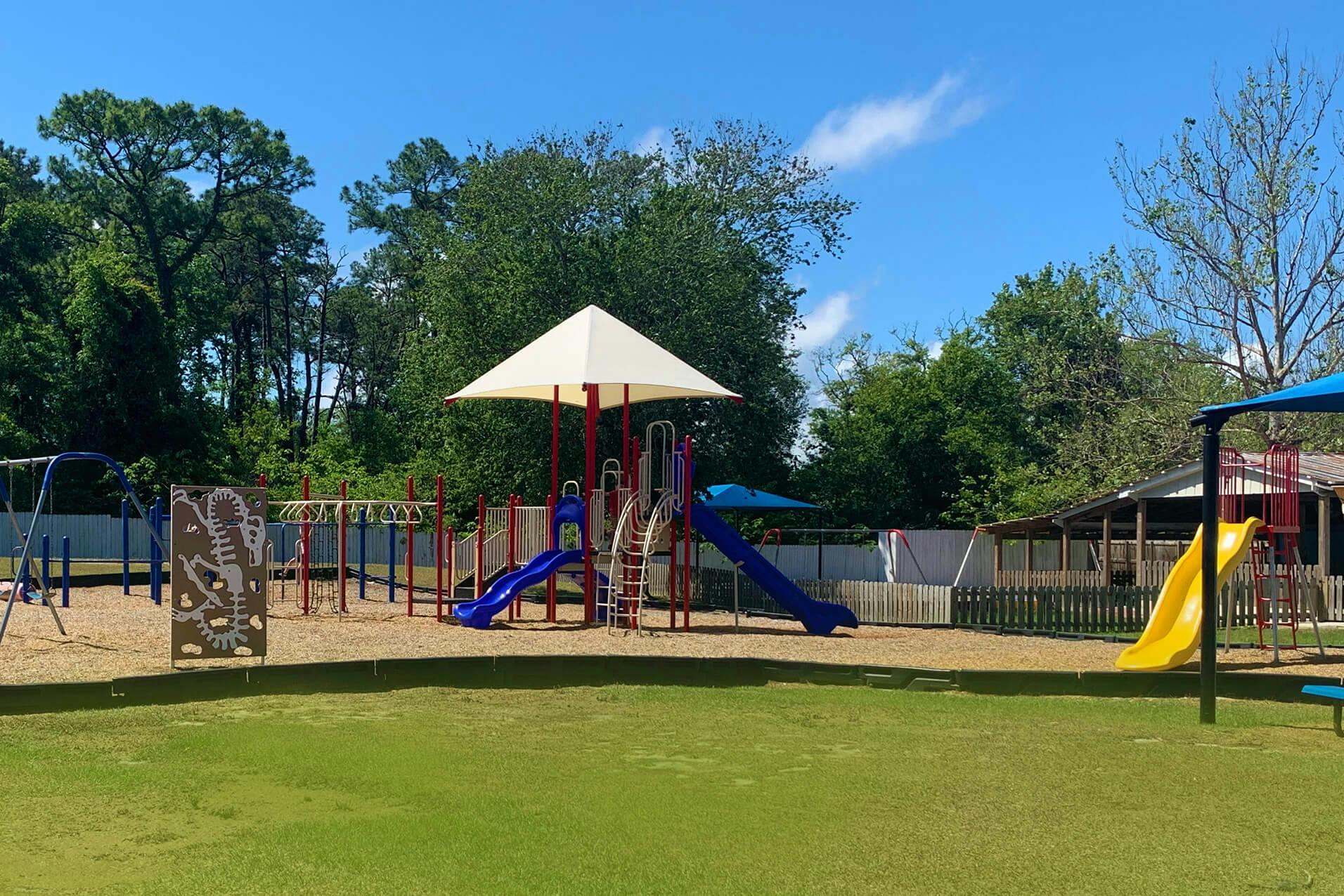 Playground with slides, swings, climbing wall, and monkey bars on a sunny day