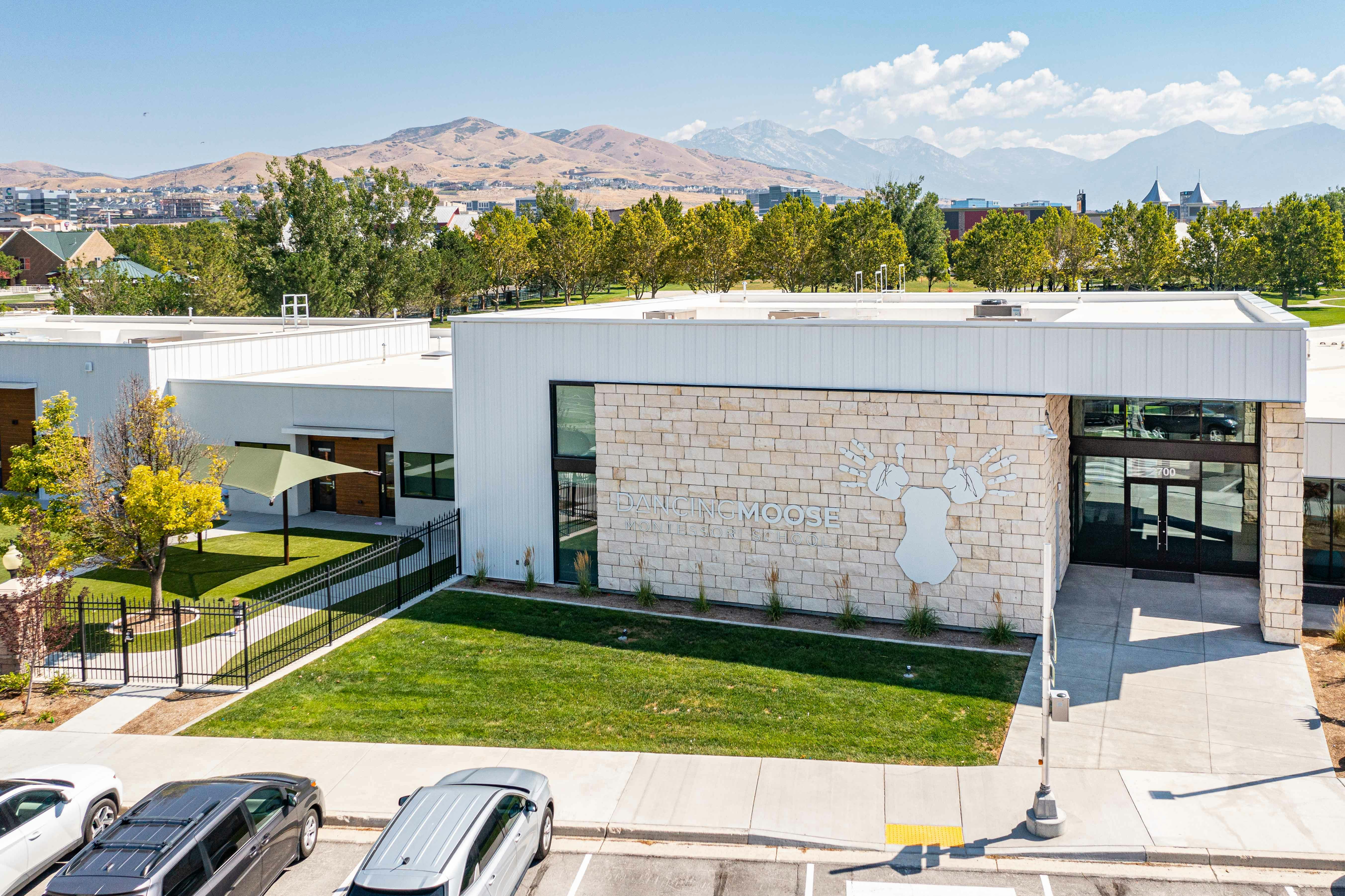 Modern building with stone facade and large windows, mountains in background