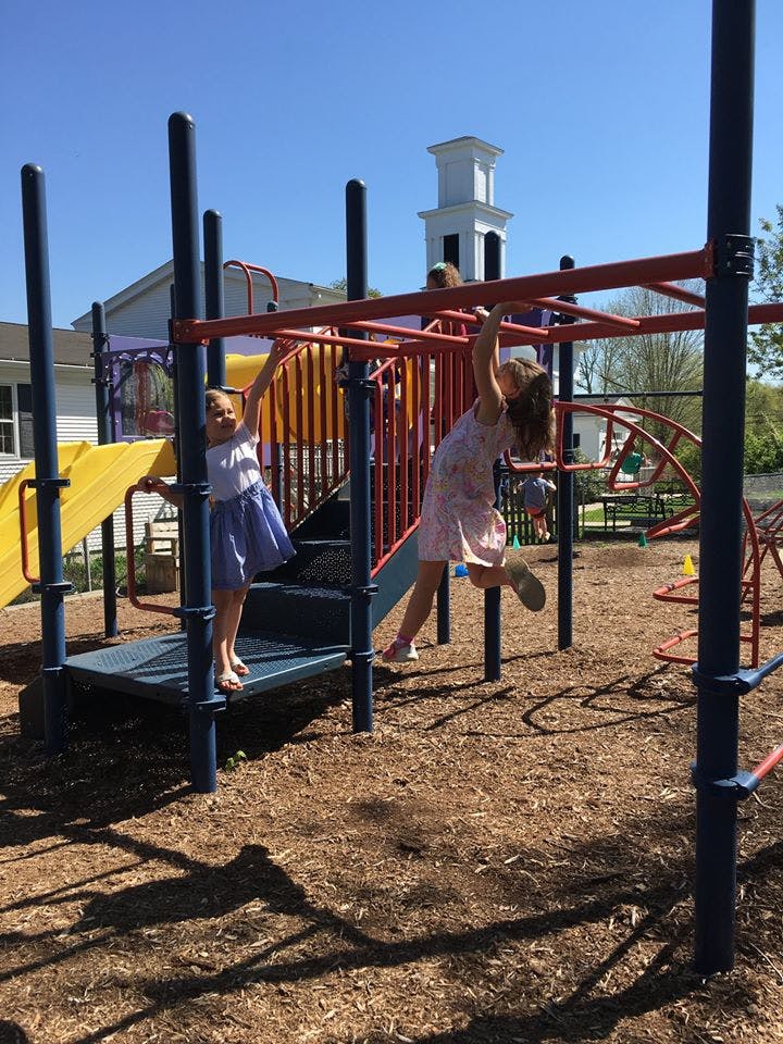Two children playing on monkey bars at a playground