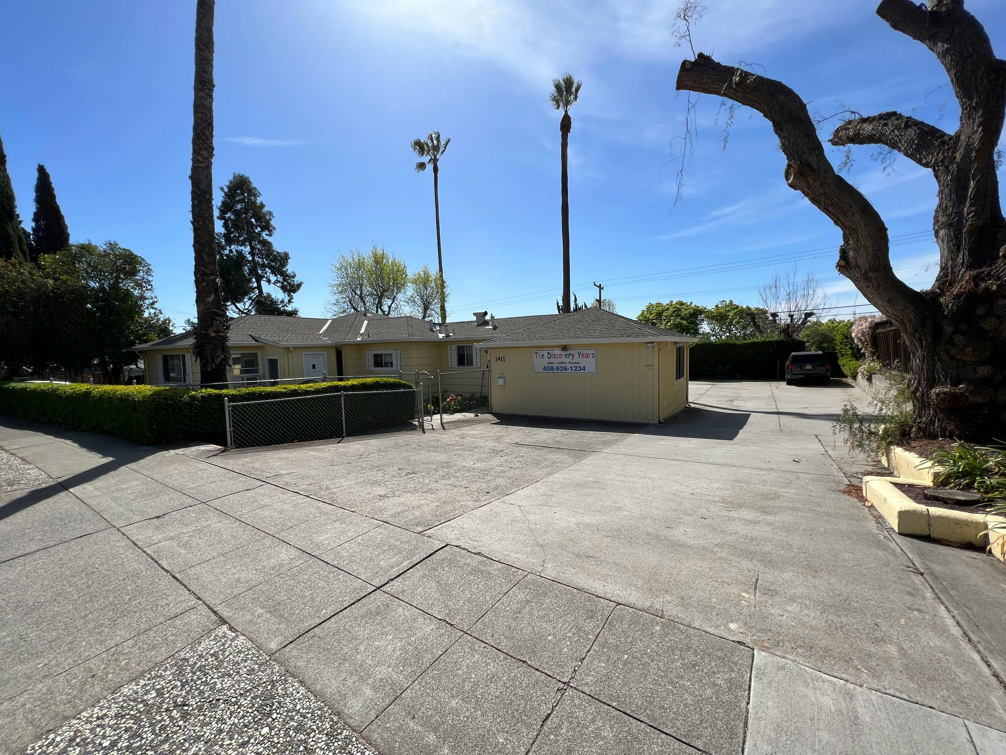 Paved driveway leading to a building with a hedge and trees