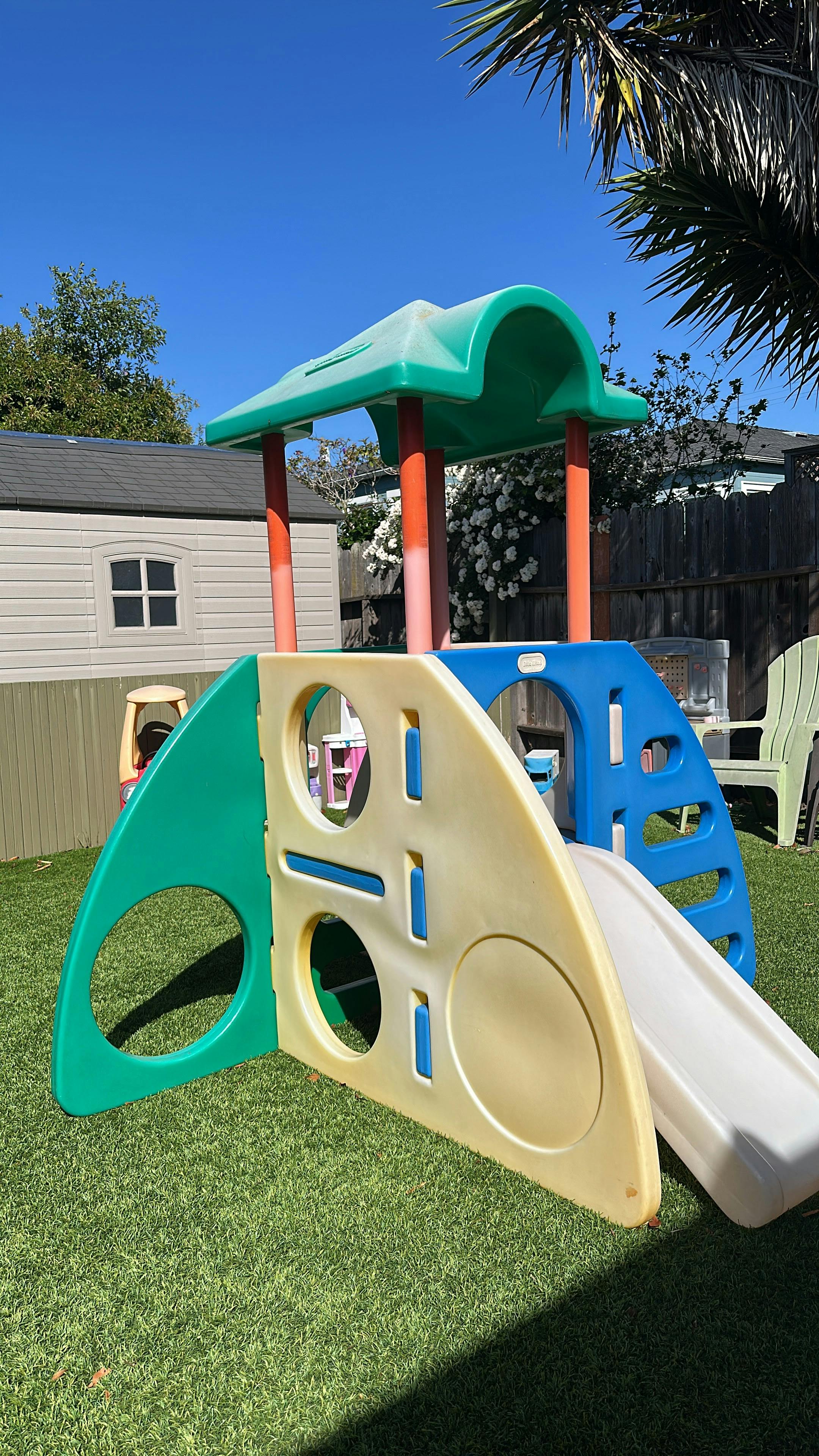 Plastic playground climber with a slide on a backyard lawn
