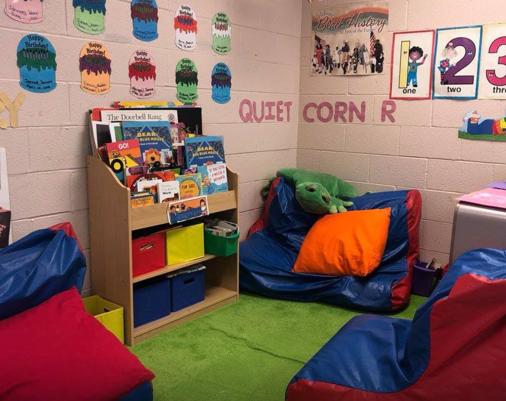 Quiet corner in a classroom with a bookshelf, beanbag chairs, and wall decorations
