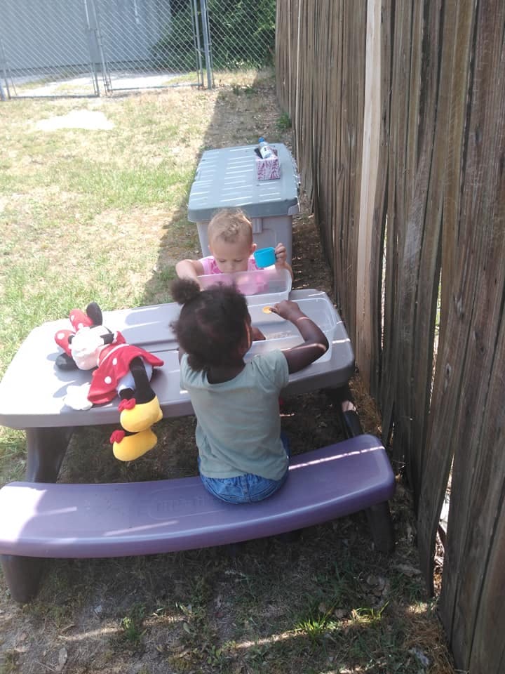 Two children playing at a small table outdoors