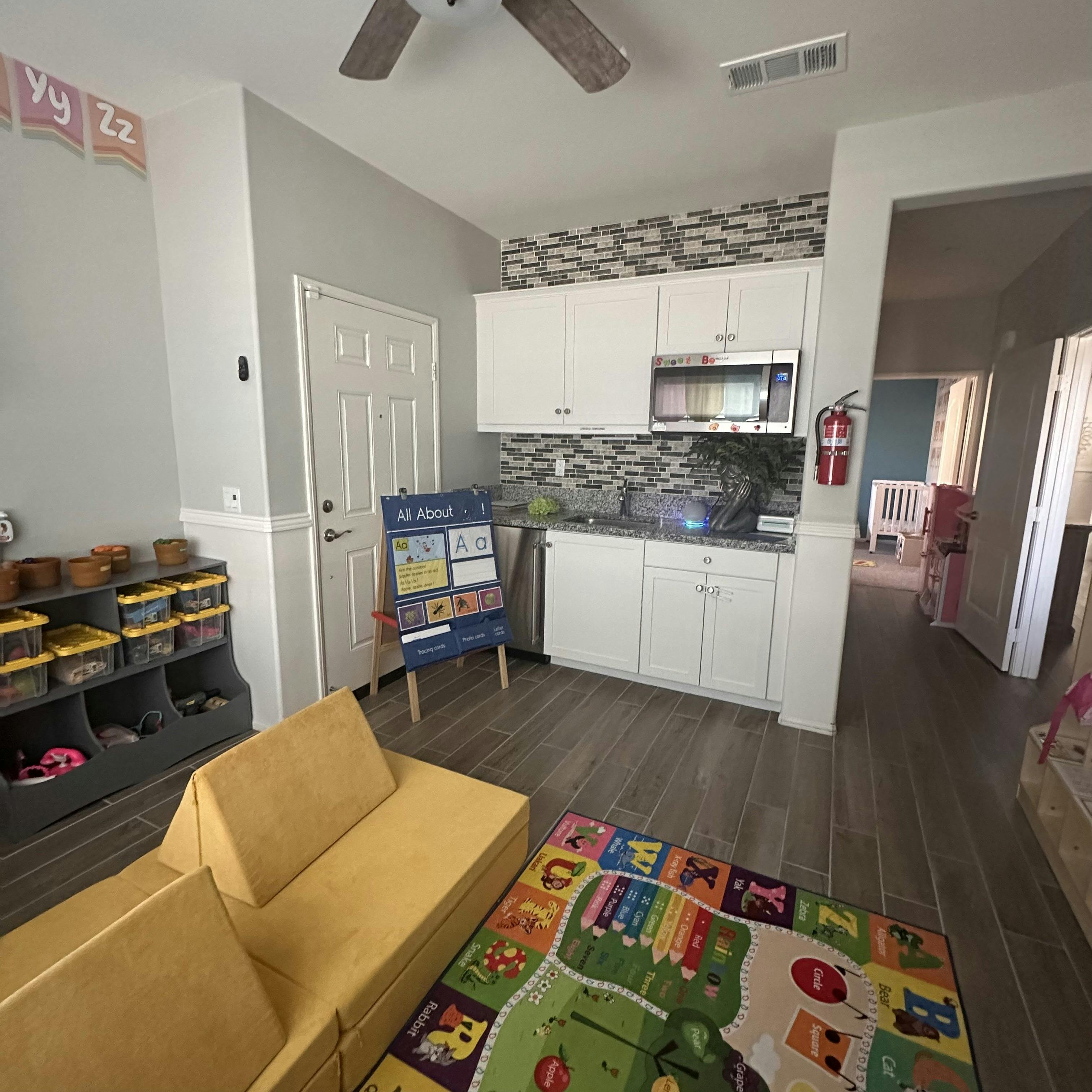 Playroom with a yellow sofa, educational rug, and teaching easel