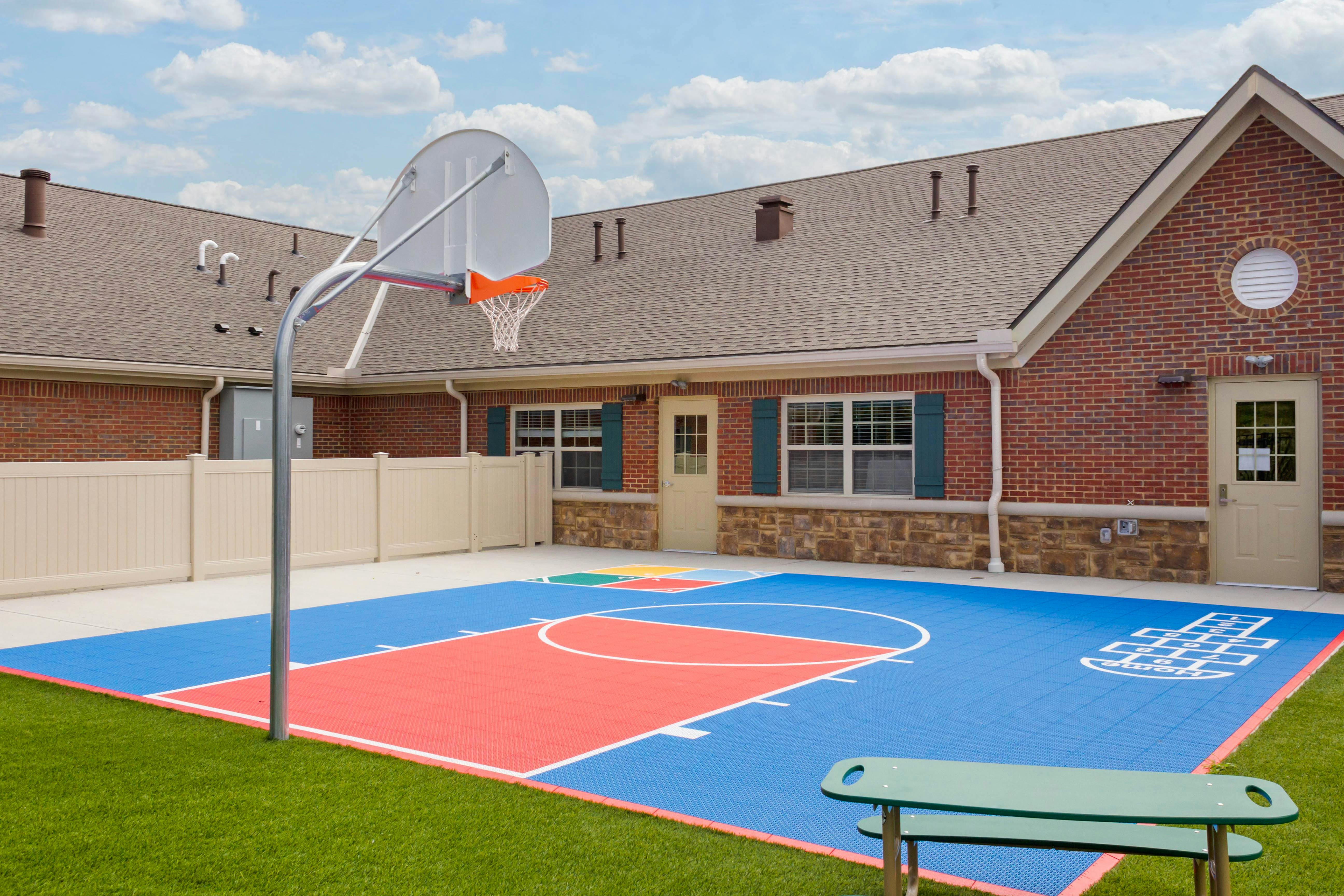 Basketball hoop over a brightly colored outdoor court with hopscotch