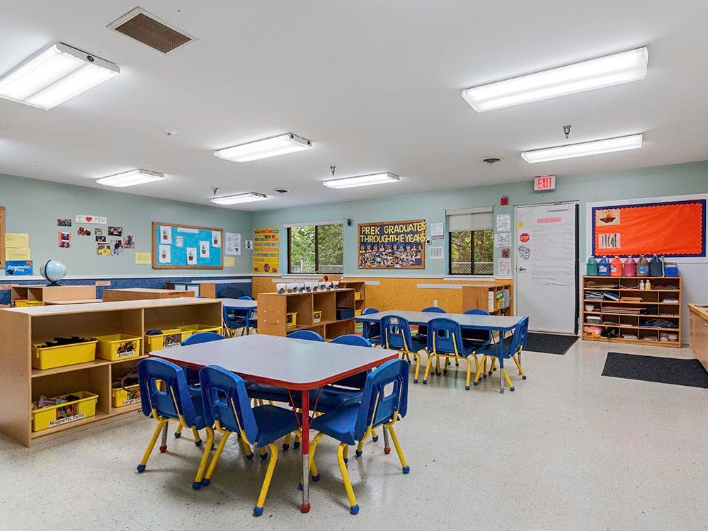 Classroom with small tables and chairs, shelves, and educational posters