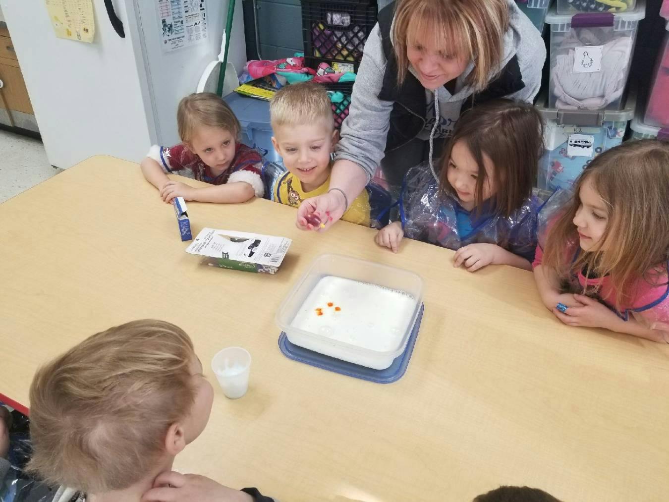 Adult and children gathered around a table looking at an experiment