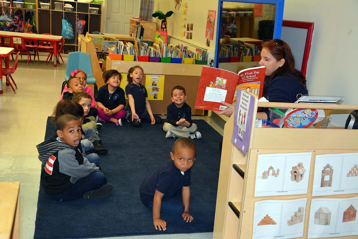 Adult reading a book to a group of children in a classroom