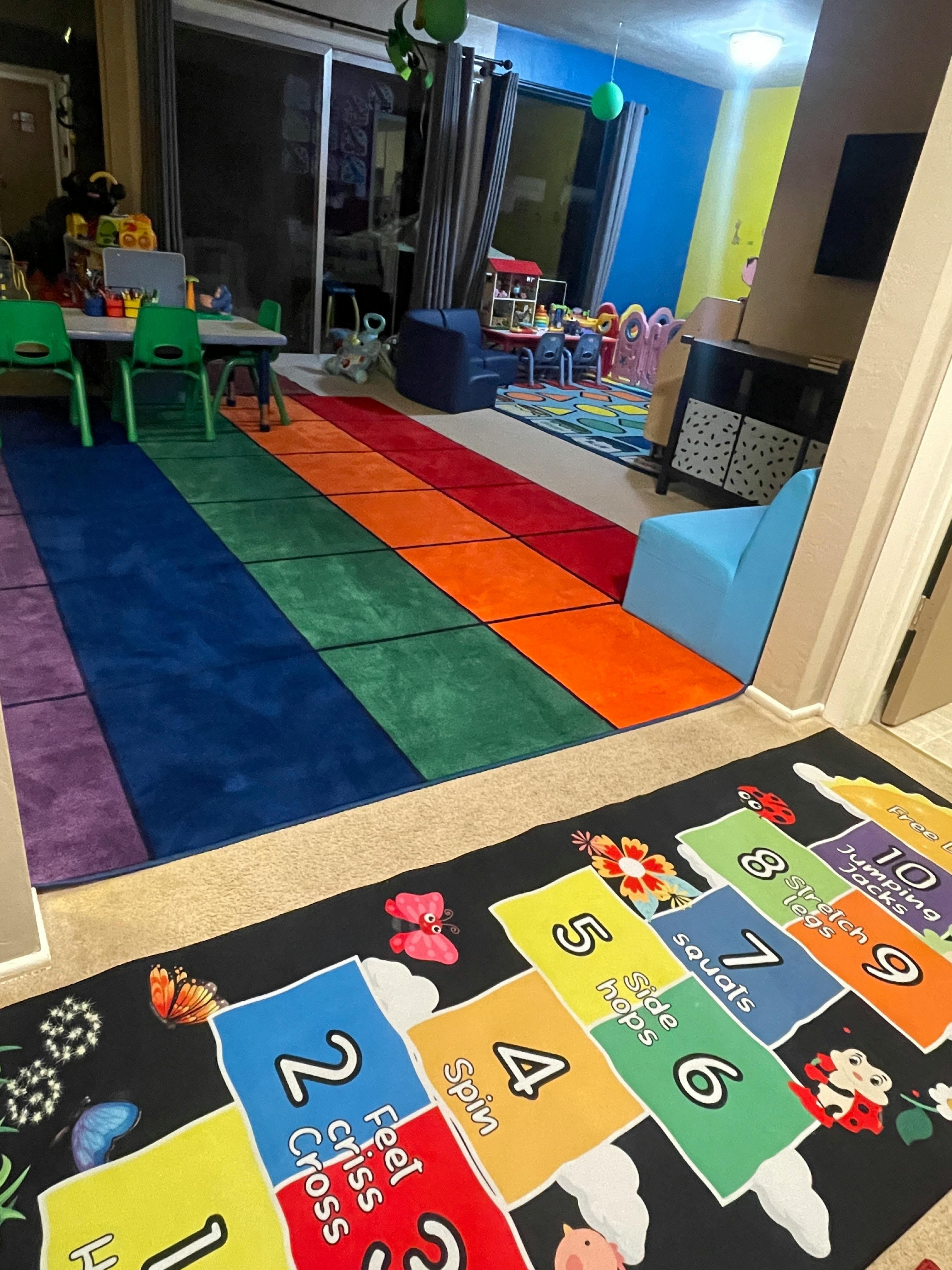 Playroom with colorful rugs, small table and chairs, and activity mat