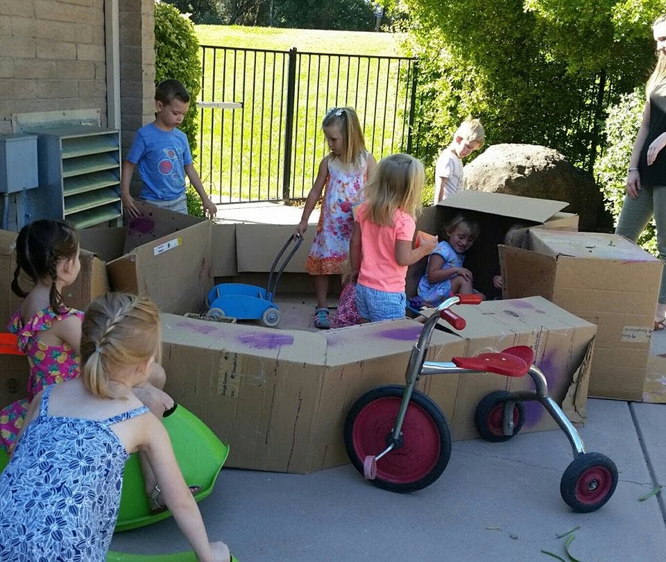 Children playing with cardboard boxes outdoors