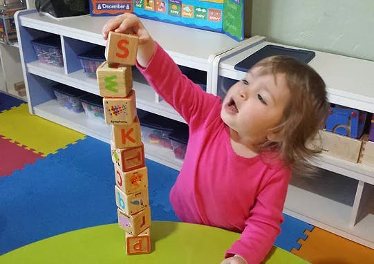 Child stacking alphabet blocks in a classroom