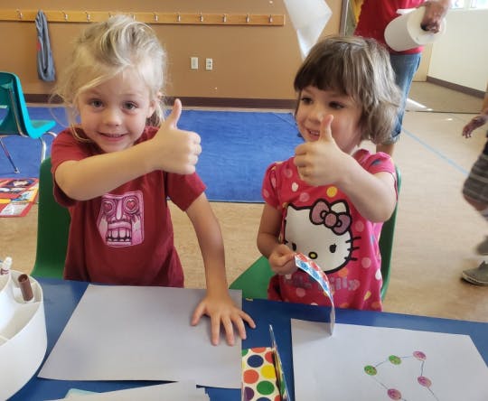 Two children giving thumbs up at a table