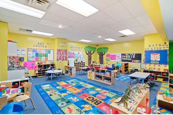 Colorful classroom with a large alphabet rug, tables, and learning centers
