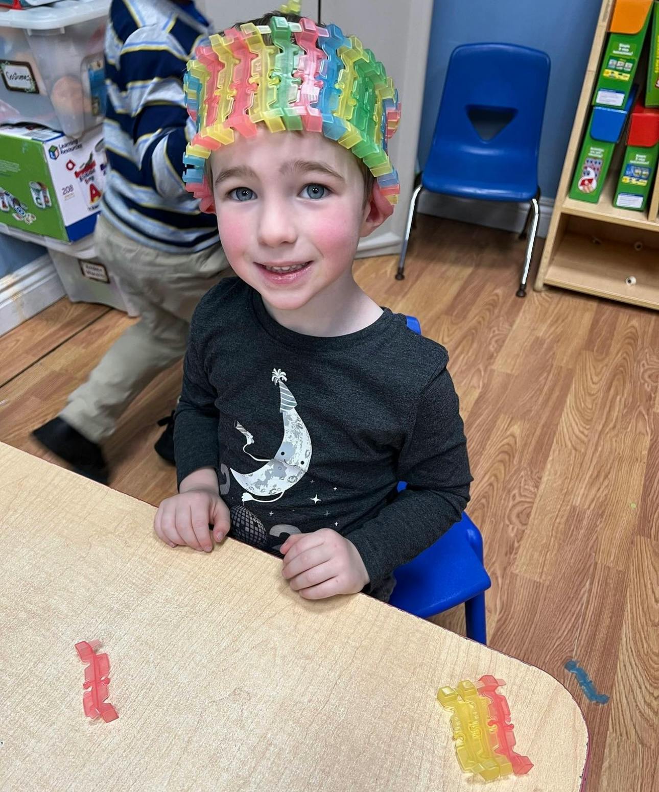 Child wearing a colorful hat sitting at a table