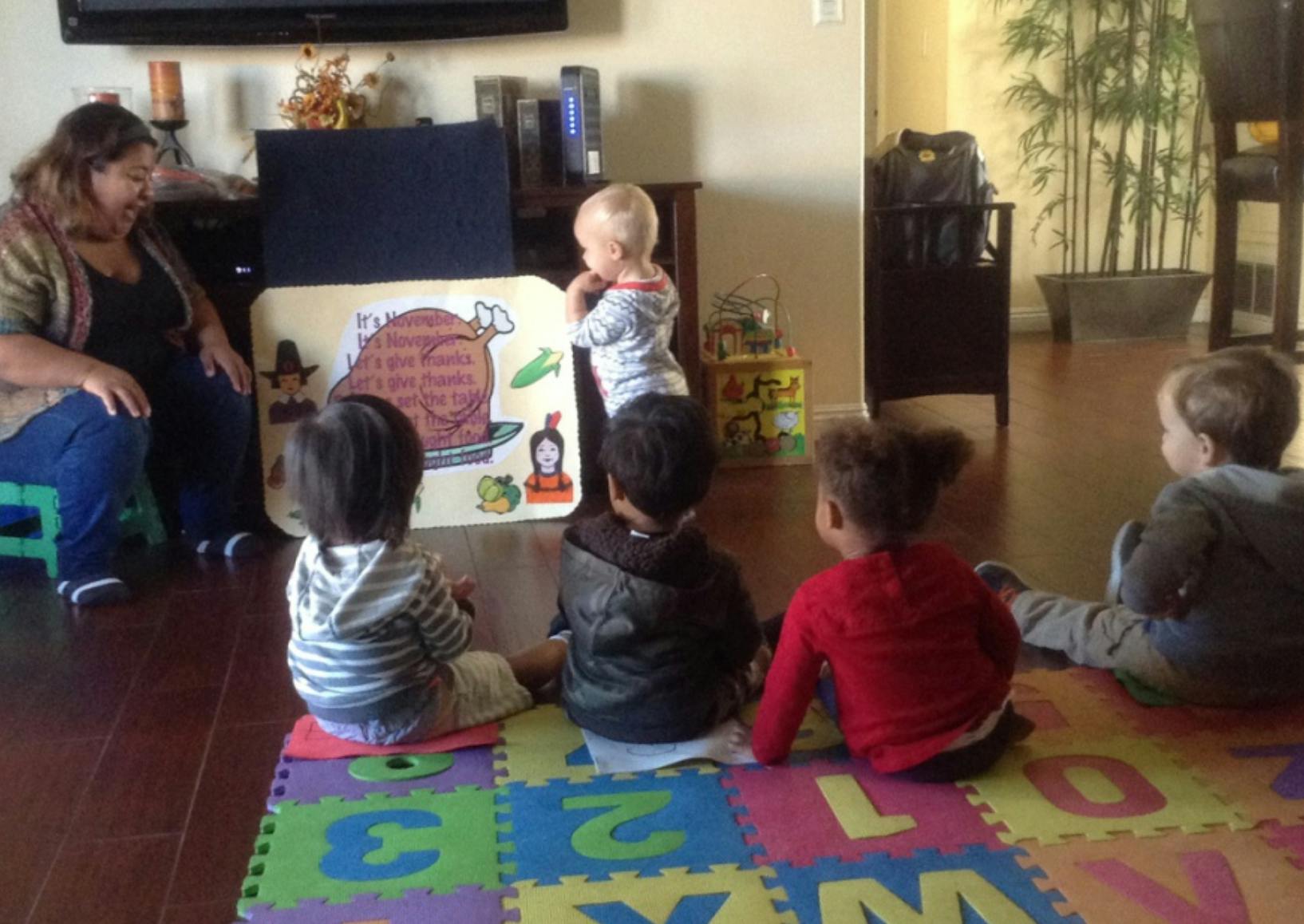 Adult and children looking at a Thanksgiving-themed felt board