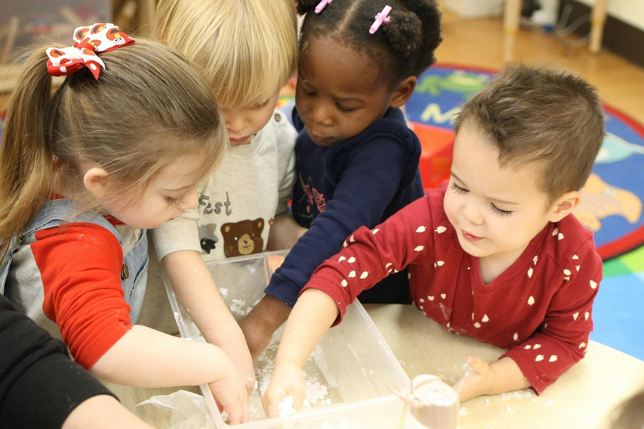 Four children playing with a sensory bin