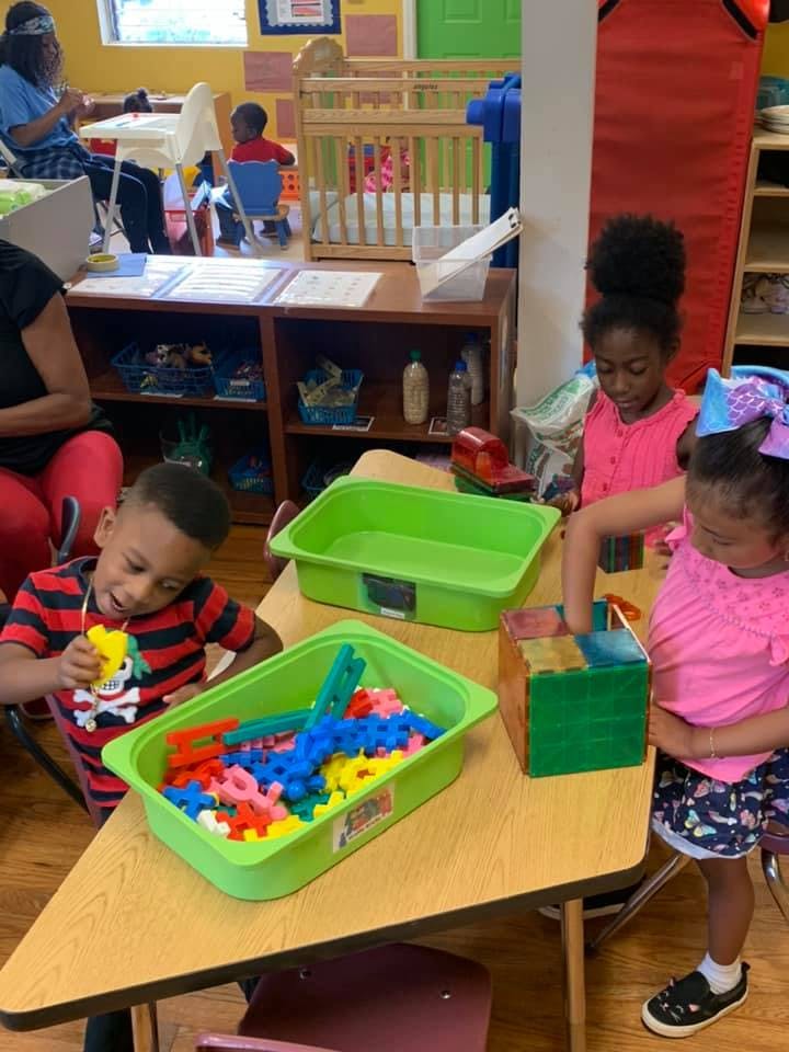 Children playing with colorful toys at a table in a classroom