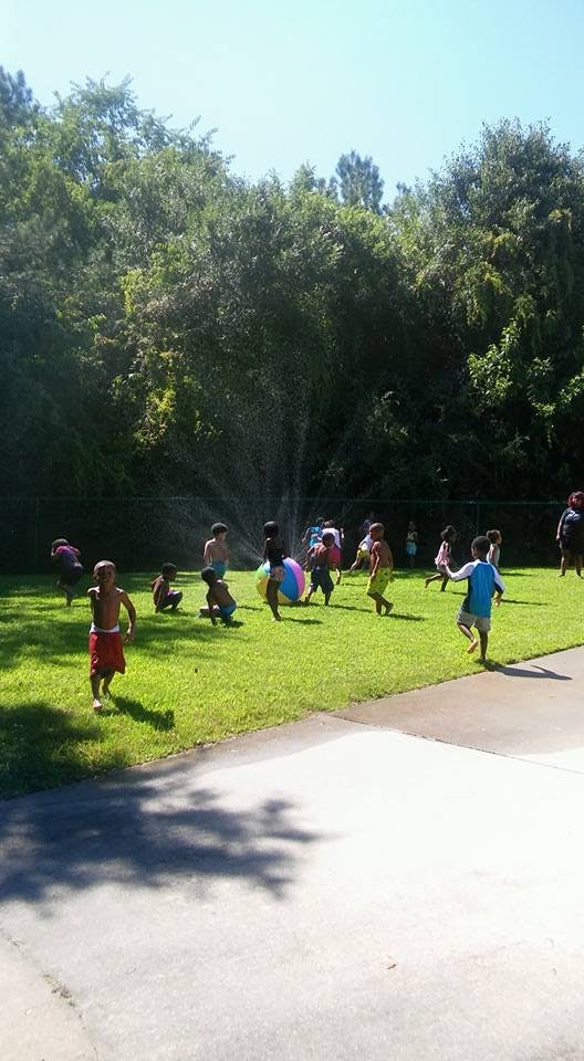 Children playing in a sprinkler on a grassy lawn