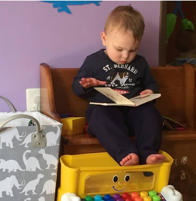 Child sitting on a bench, looking at a book