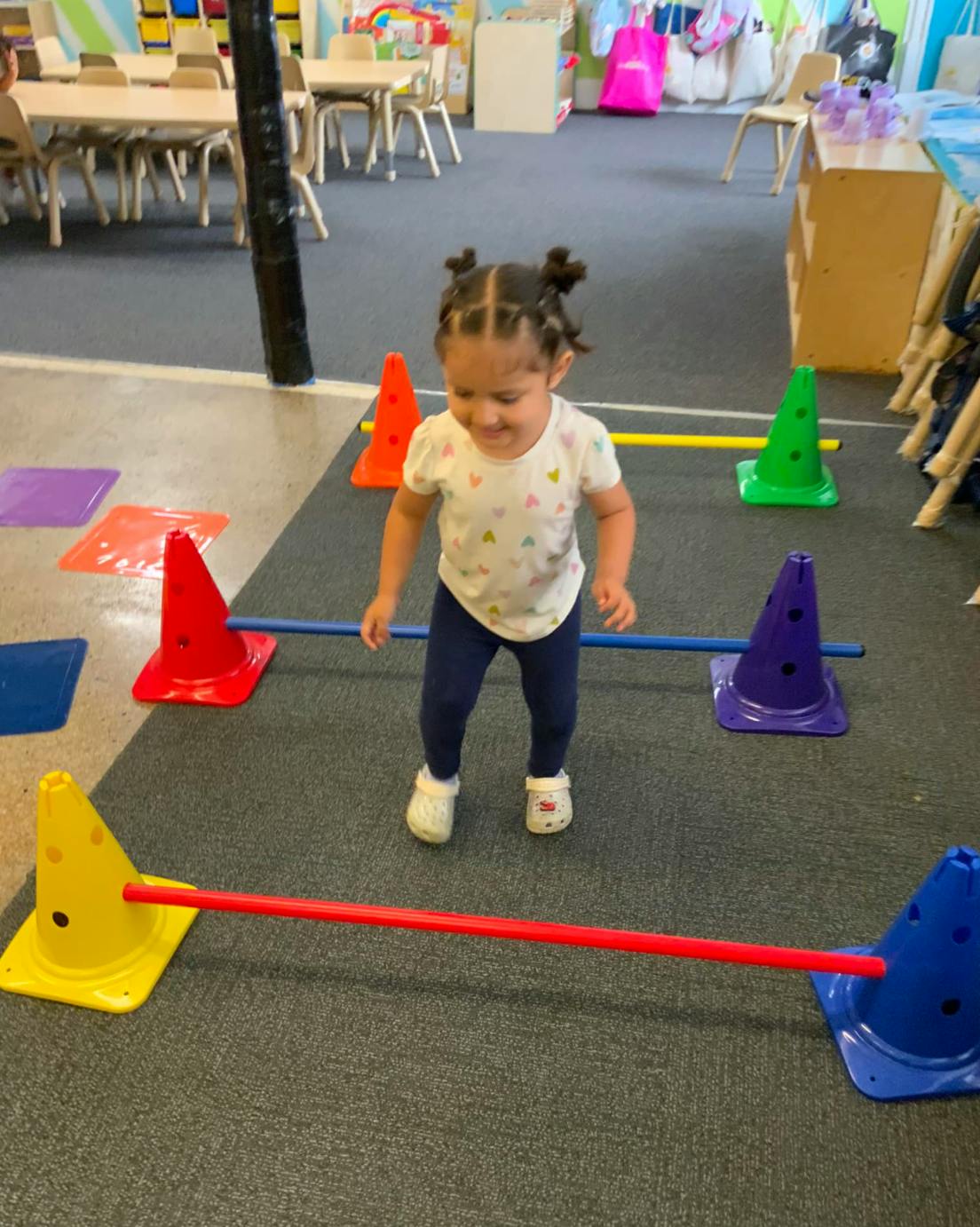 Child moving through an obstacle course of cones and poles in a classroom