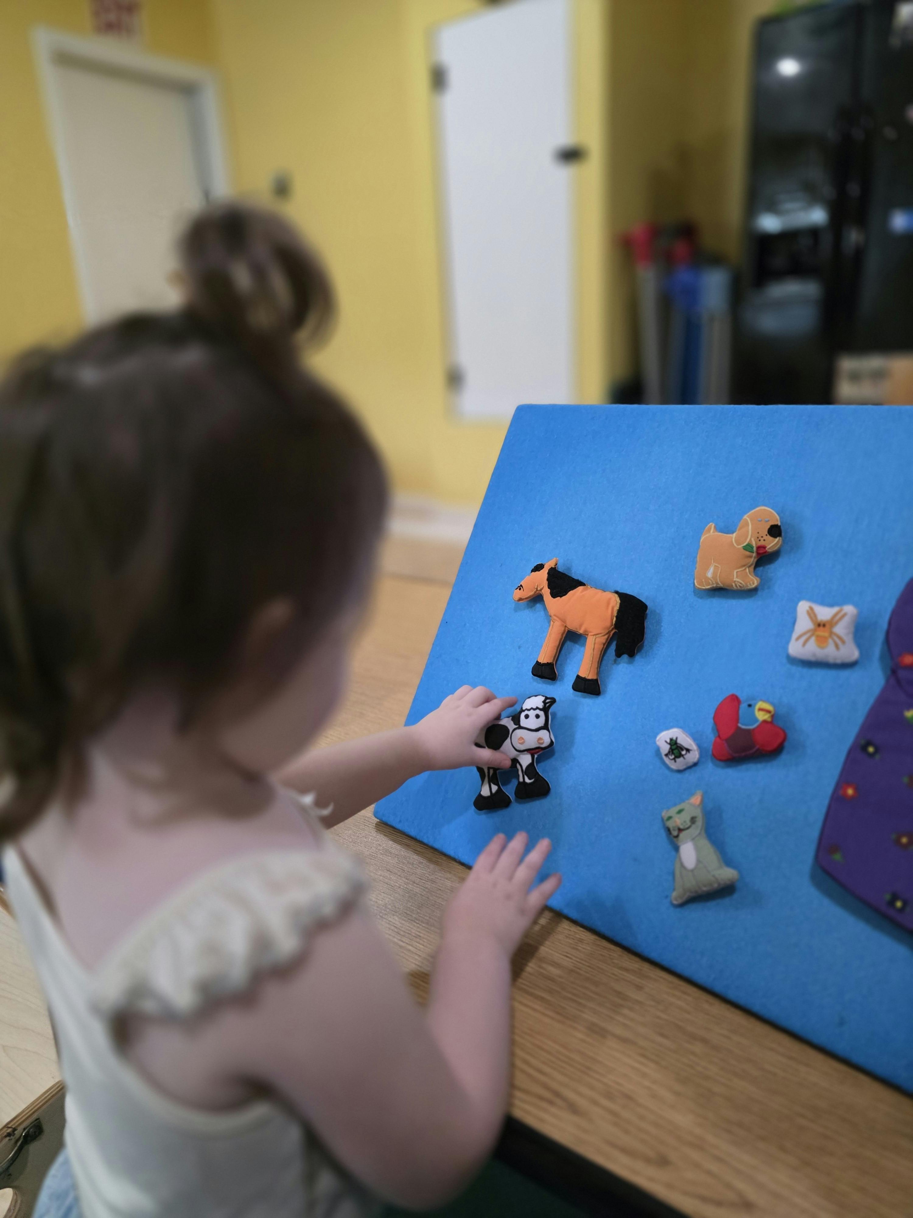 Child placing felt animal shapes on a blue board