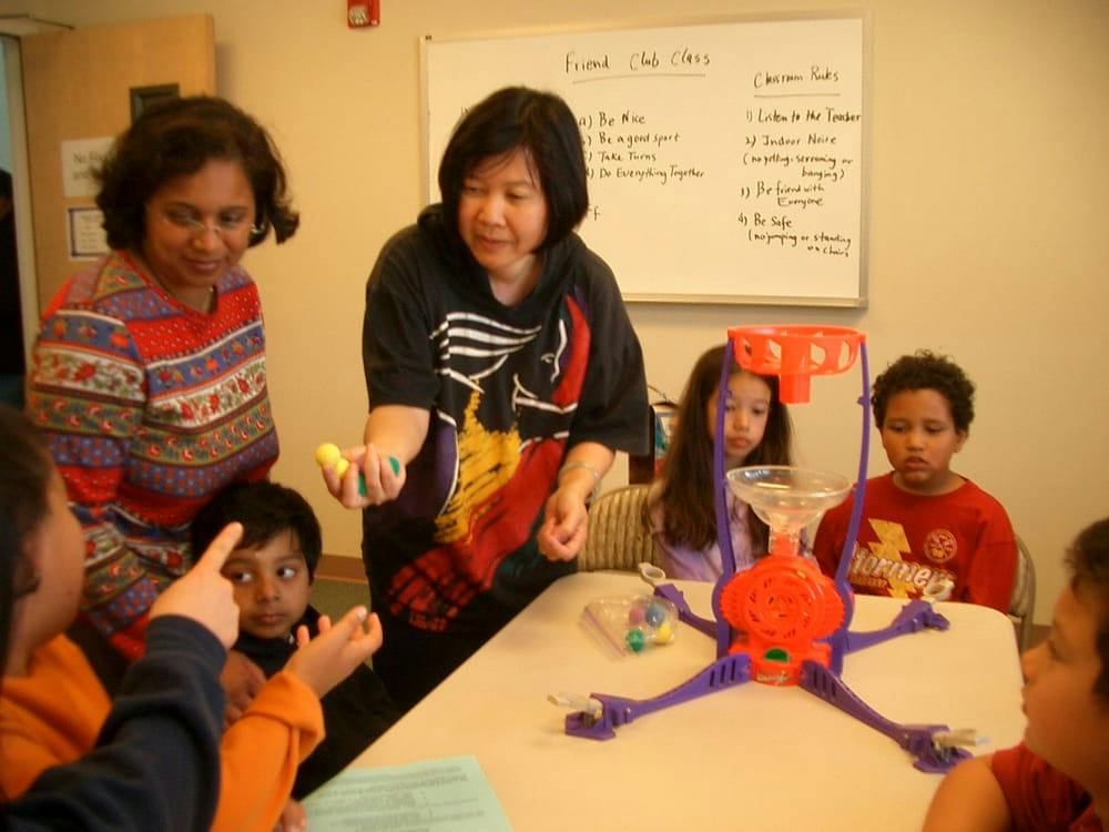 Adults and children gathered around a table with a game