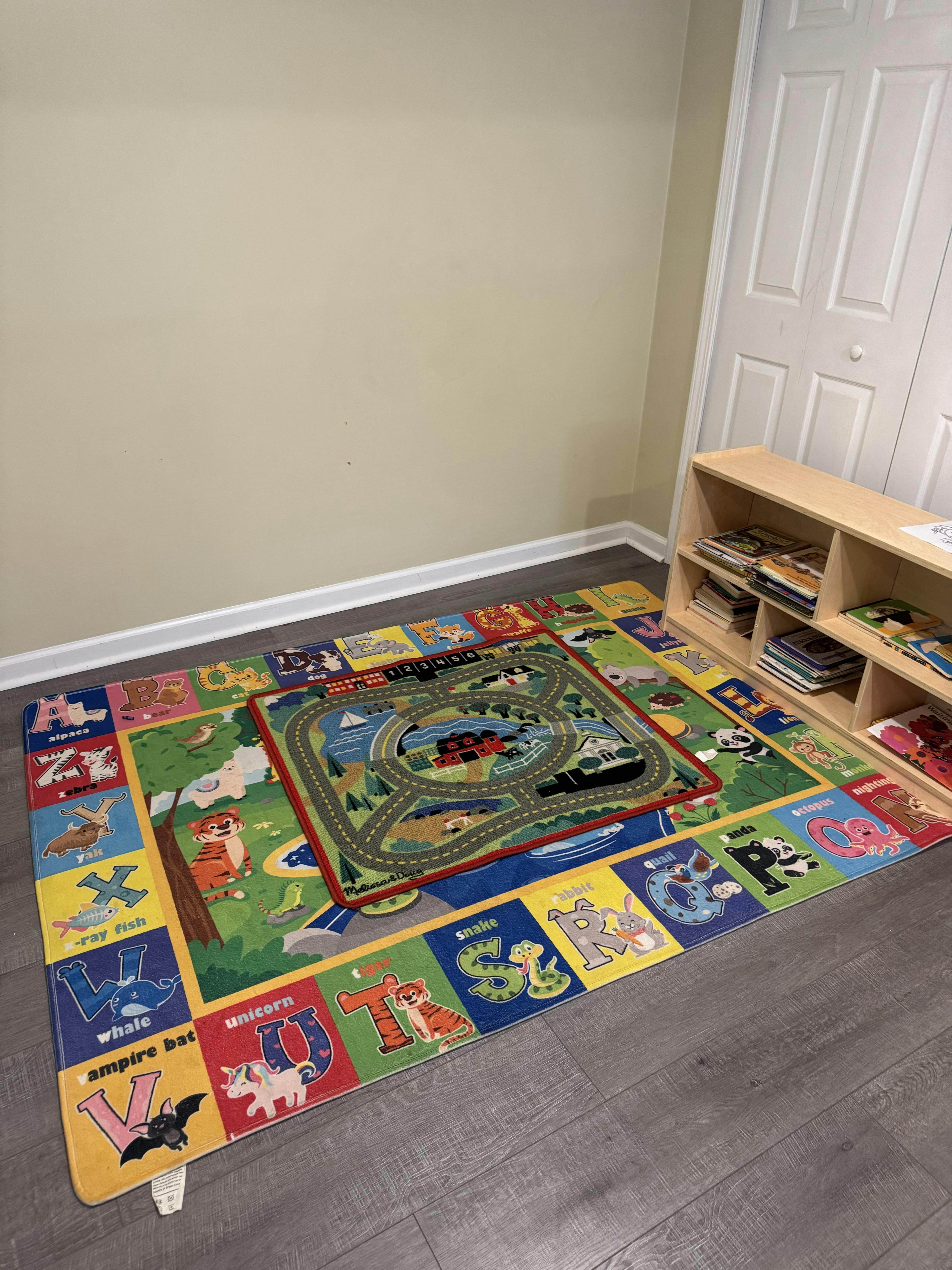 Alphabet rug with a smaller playmat on top in a room with a bookshelf