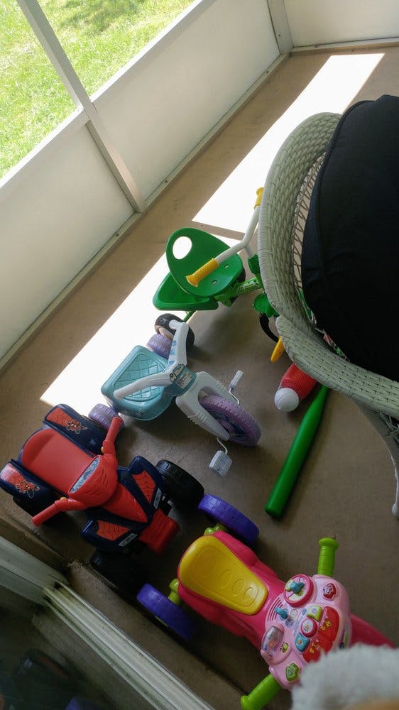 Multiple children's toys on a floor, including tricycles and ride-ons