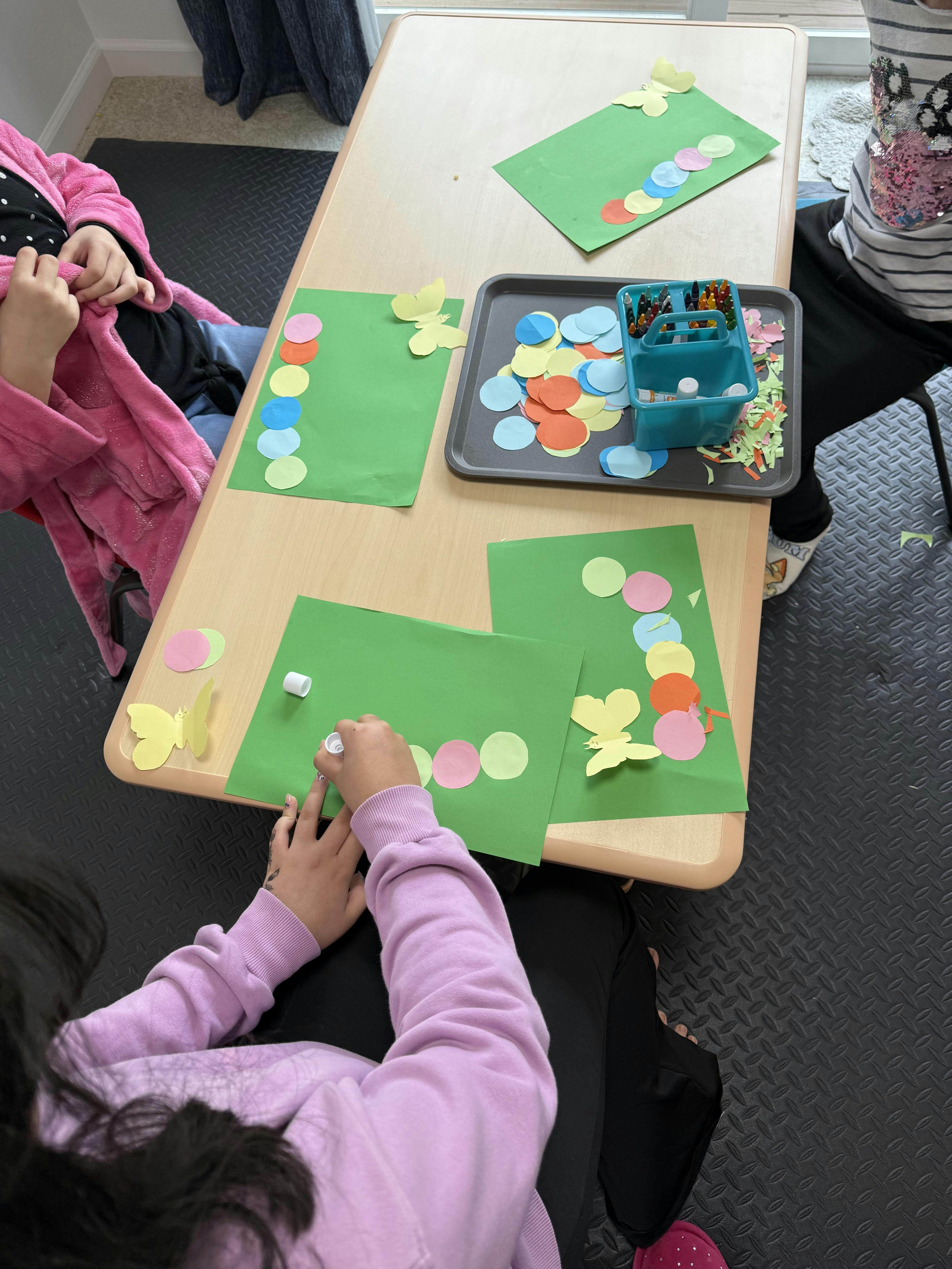 Children doing a craft project with construction paper circles and butterflies