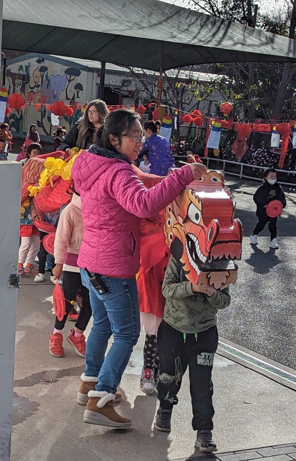 Person helping a child hold a dragon head costume