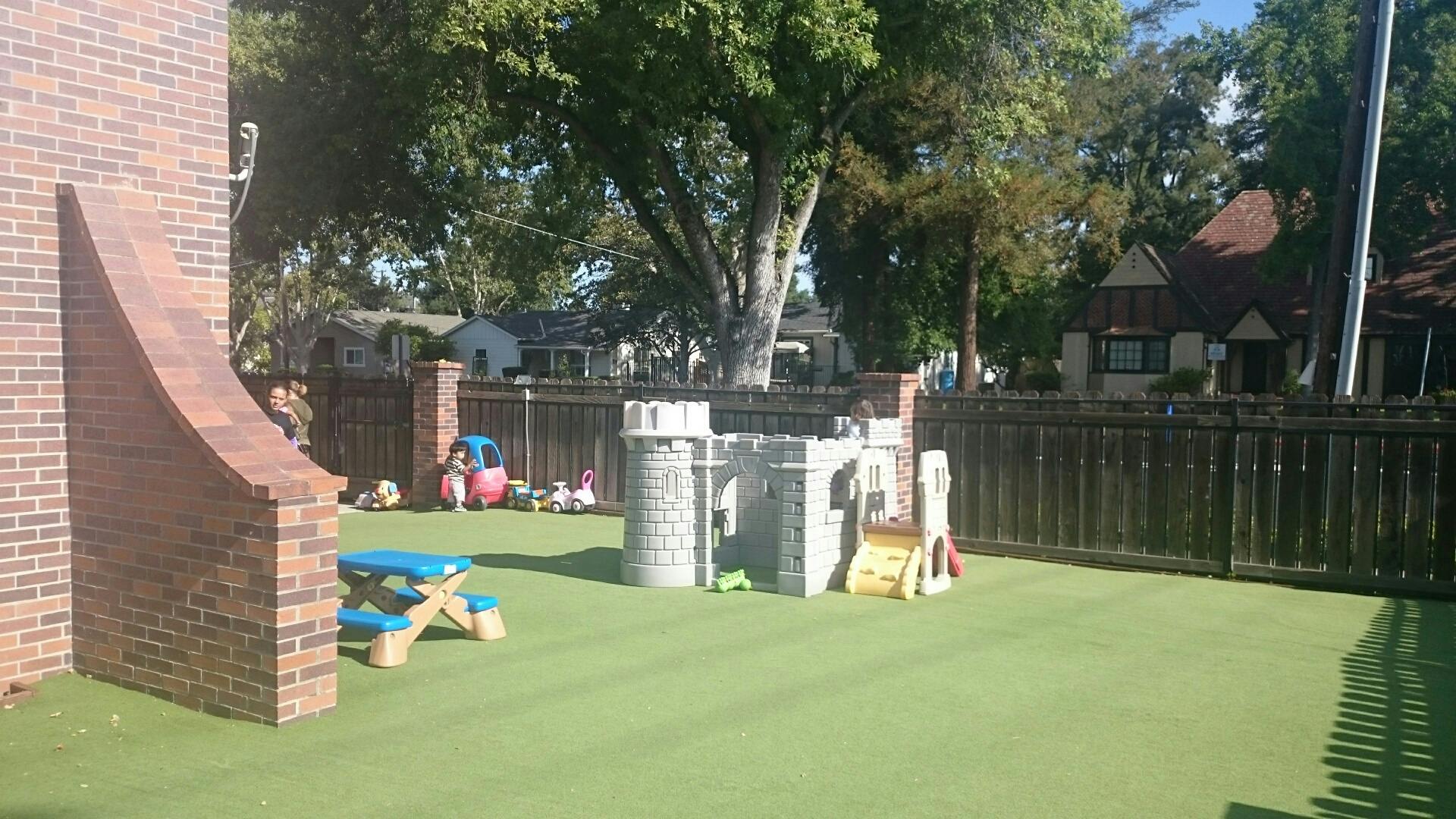 Outdoor play area with artificial turf, play castle, and picnic table