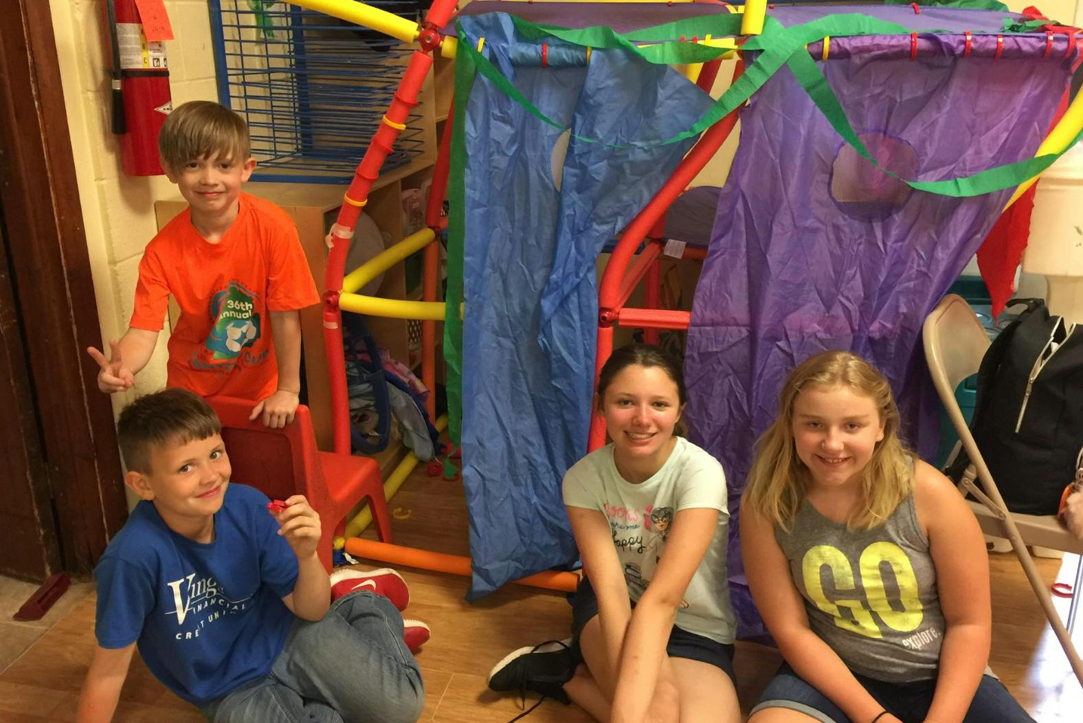 Four children in a room with a colorful play structure