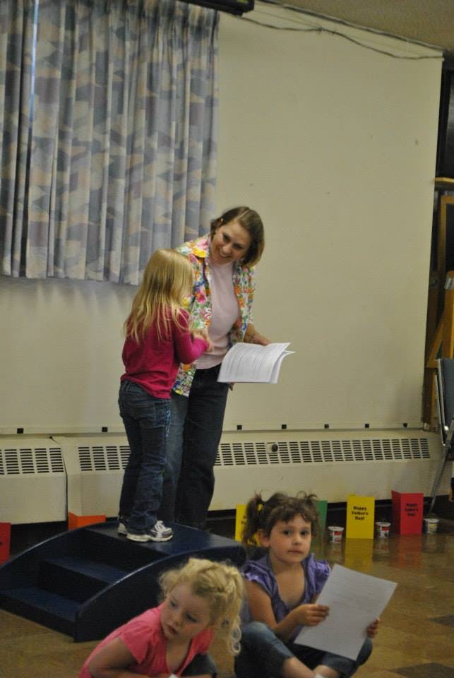 Adult and child standing on a platform, looking at a book