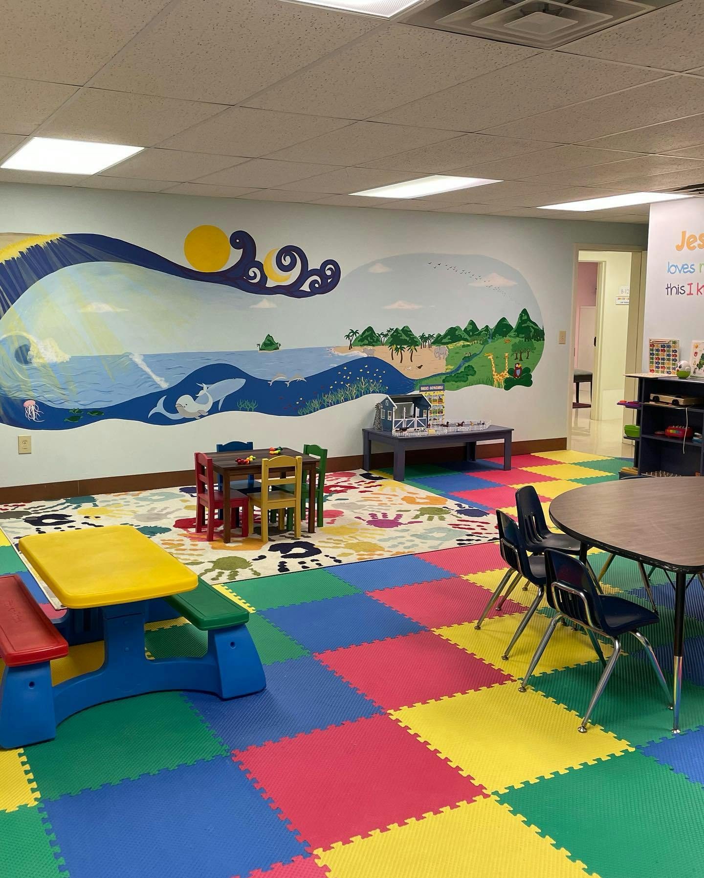 Children's play area with colorful floor mats and tables