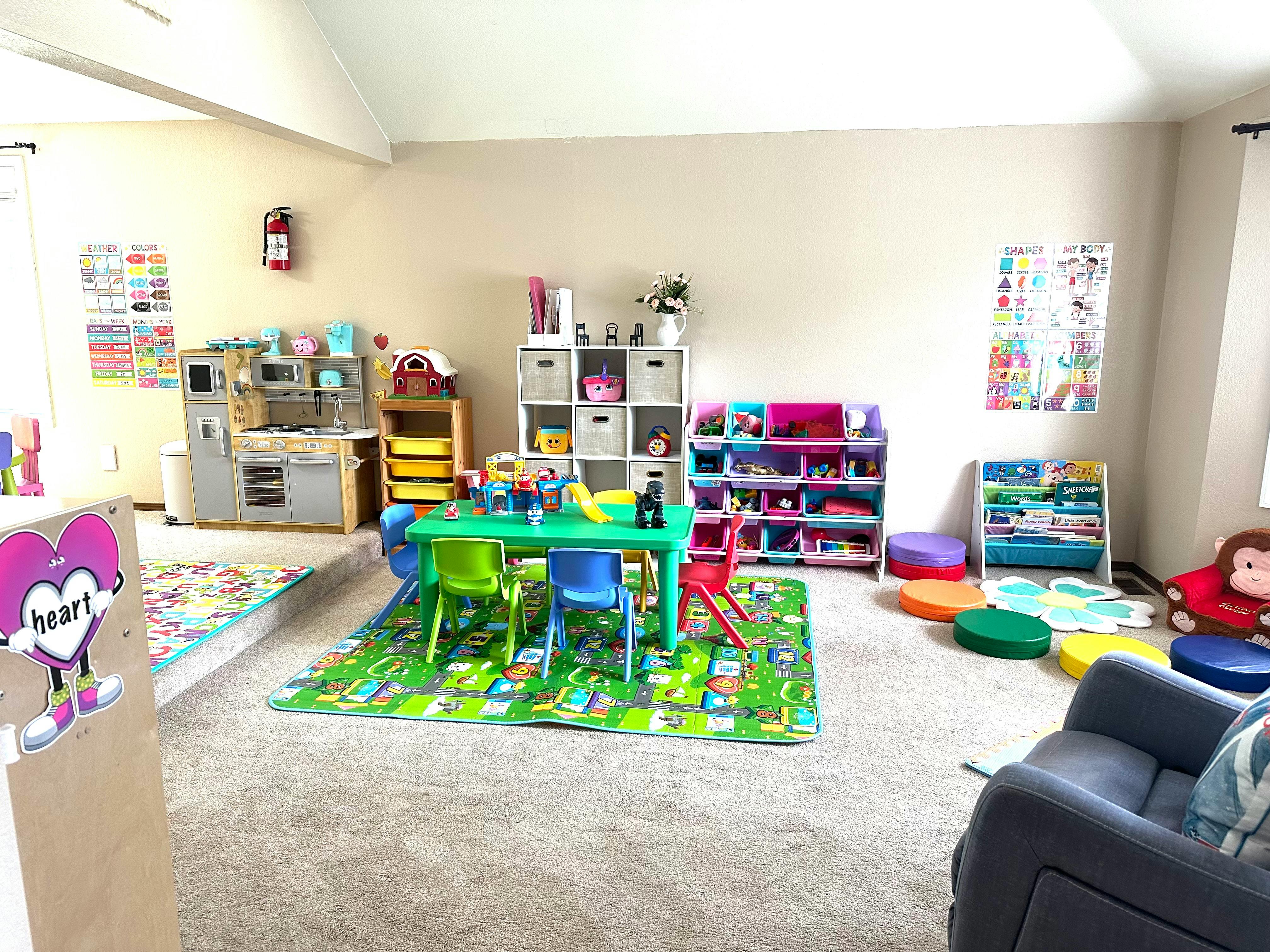 Playroom with a green table and chairs, toy kitchen, and storage shelves