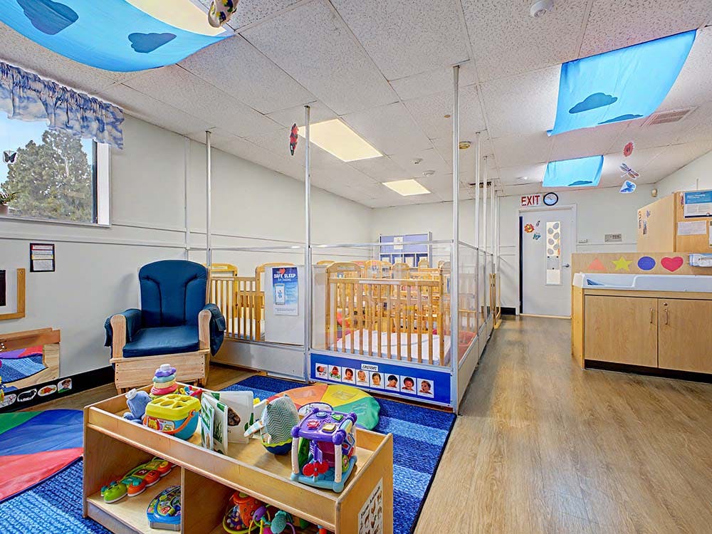daycare classroom with multiple cribs, a changing station, and toys