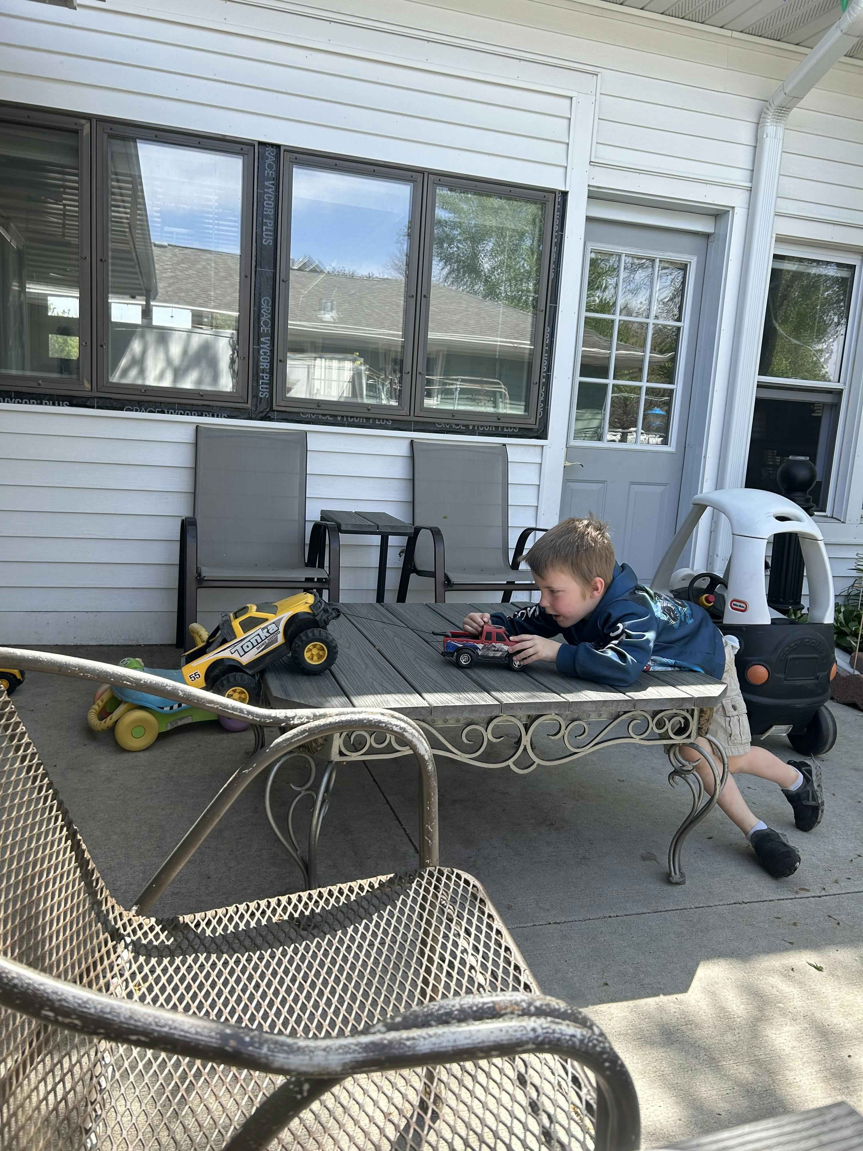 Child playing with toy cars on an outdoor table