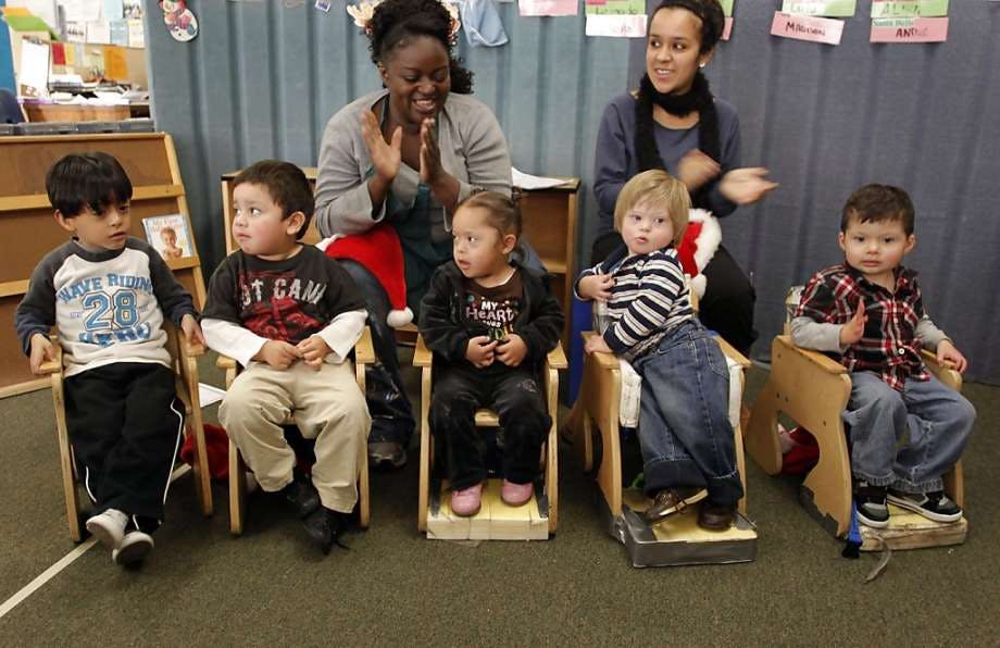 Two people clapping while children sit in chairs
