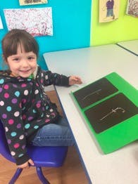 Child sitting at a table with a green folder