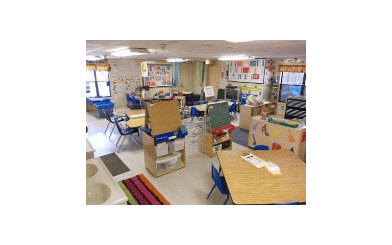 Classroom with tables, chairs, easels, and wall decorations