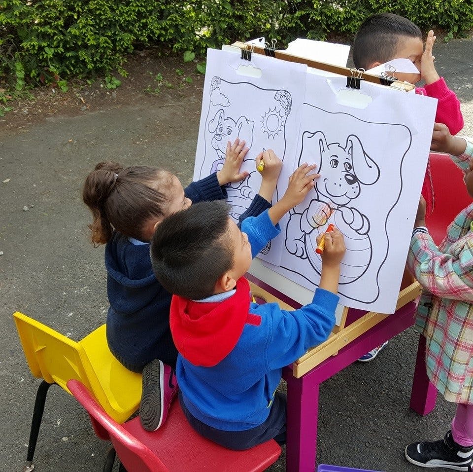 Children coloring a large drawing of a dog on an easel