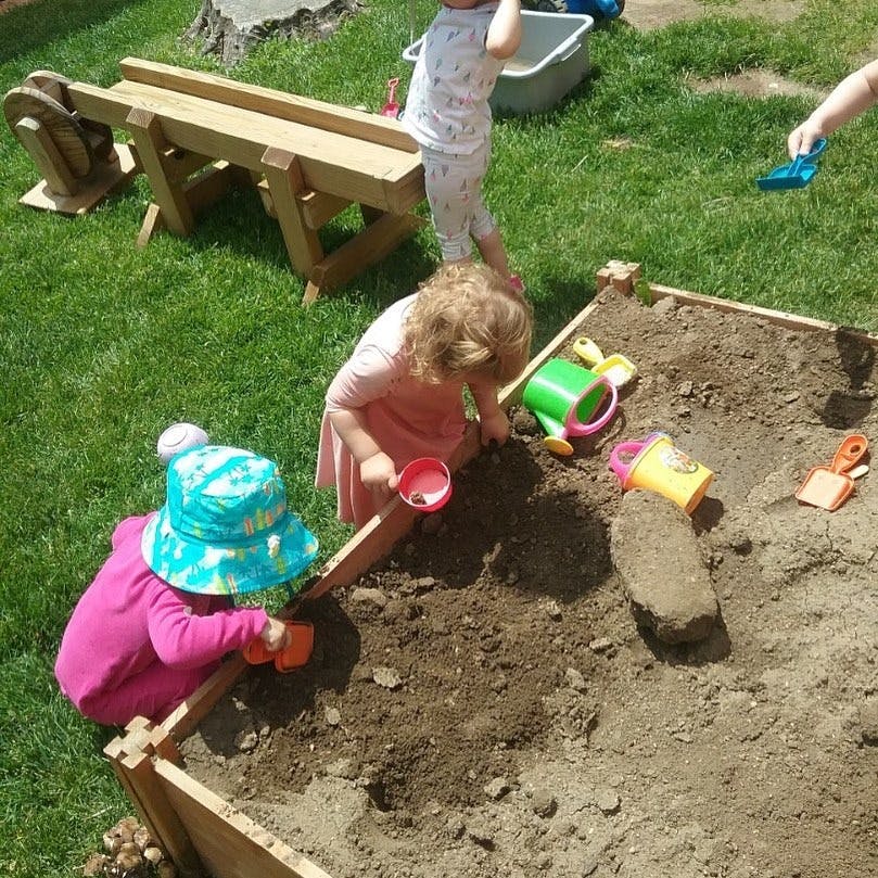 Children playing in a sandbox with toys