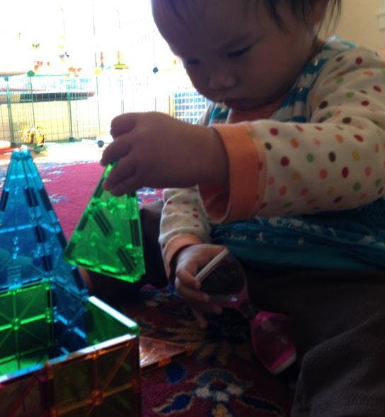 Child playing with colorful magnetic building tiles